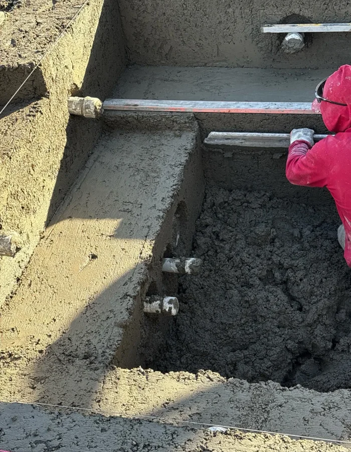 Pool contractor shaping and finishing fresh shotcrete during custom swimming pool construction in Elk Ridge, Utah.