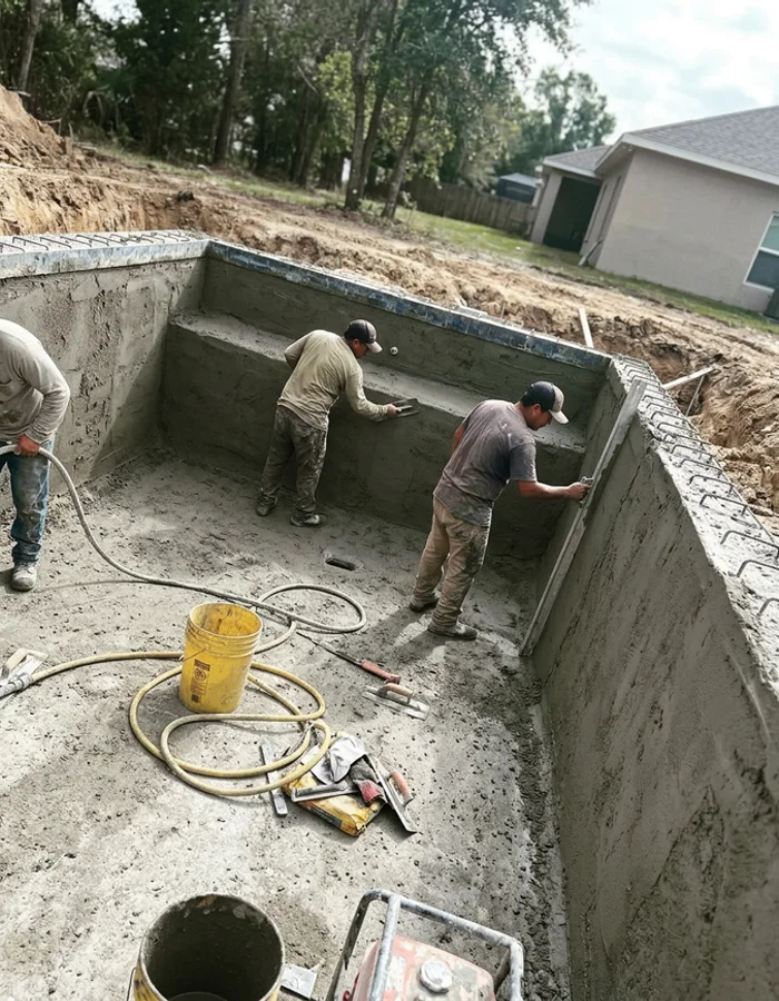 Crew finishing shotcrete work inside a new pool shell