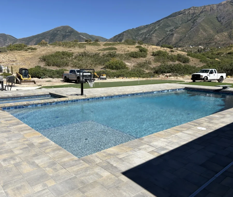 Custom swimming pool with wet deck, diving board, paver deck, and mountain views in Elk Ridge, Utah.