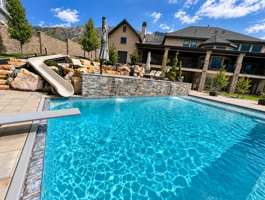 Raised spa spilling into a pool beside stone coping at a Highland home